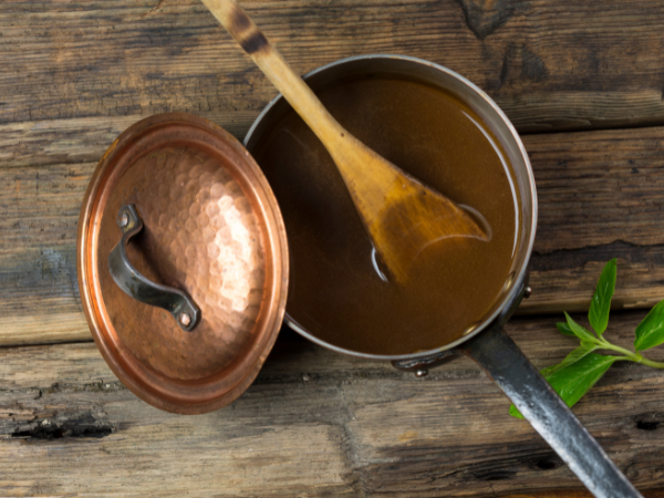 Gravy in a copper pot with a wooden spoon
